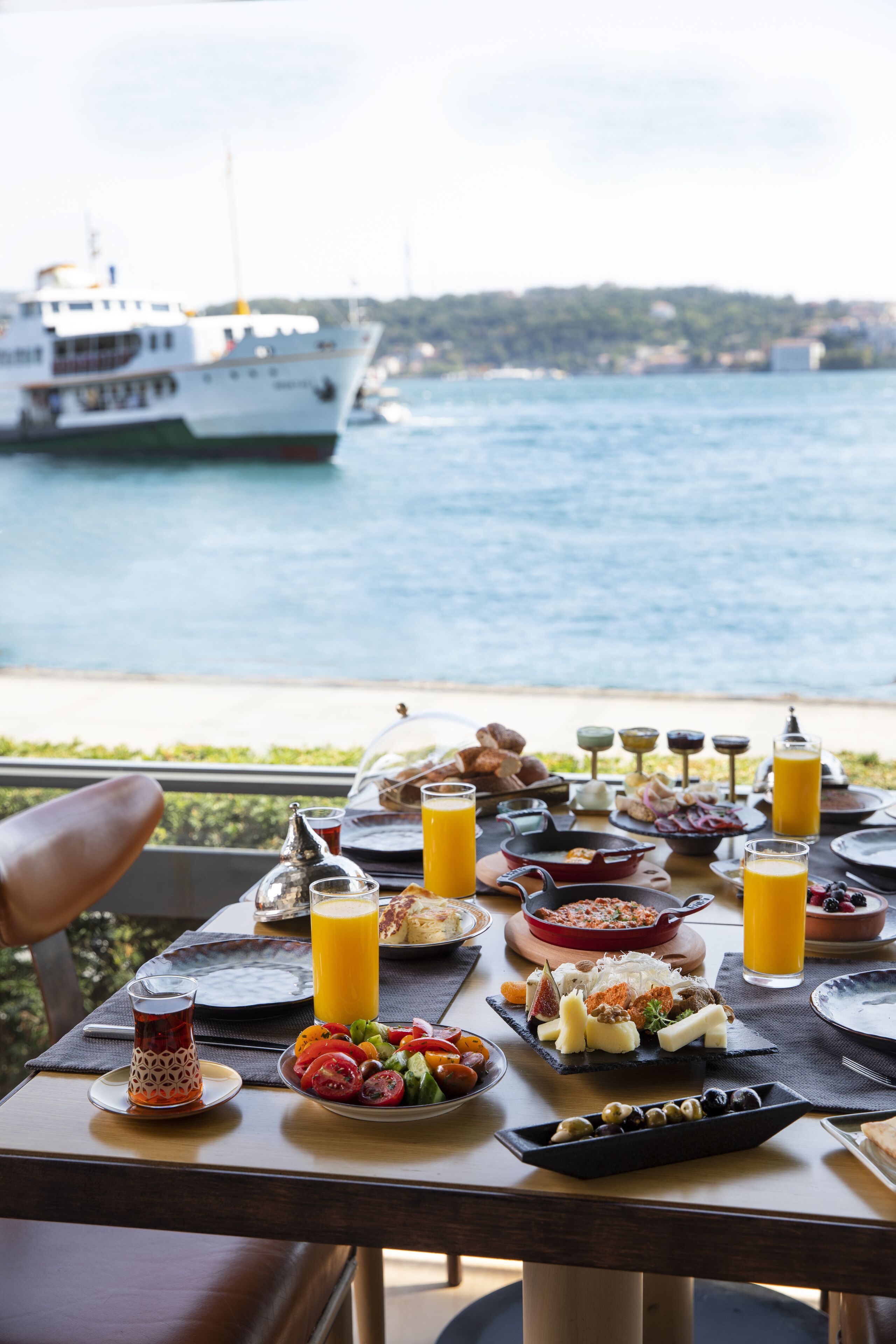 A table set with breakfast items and a view of a boat on the water.