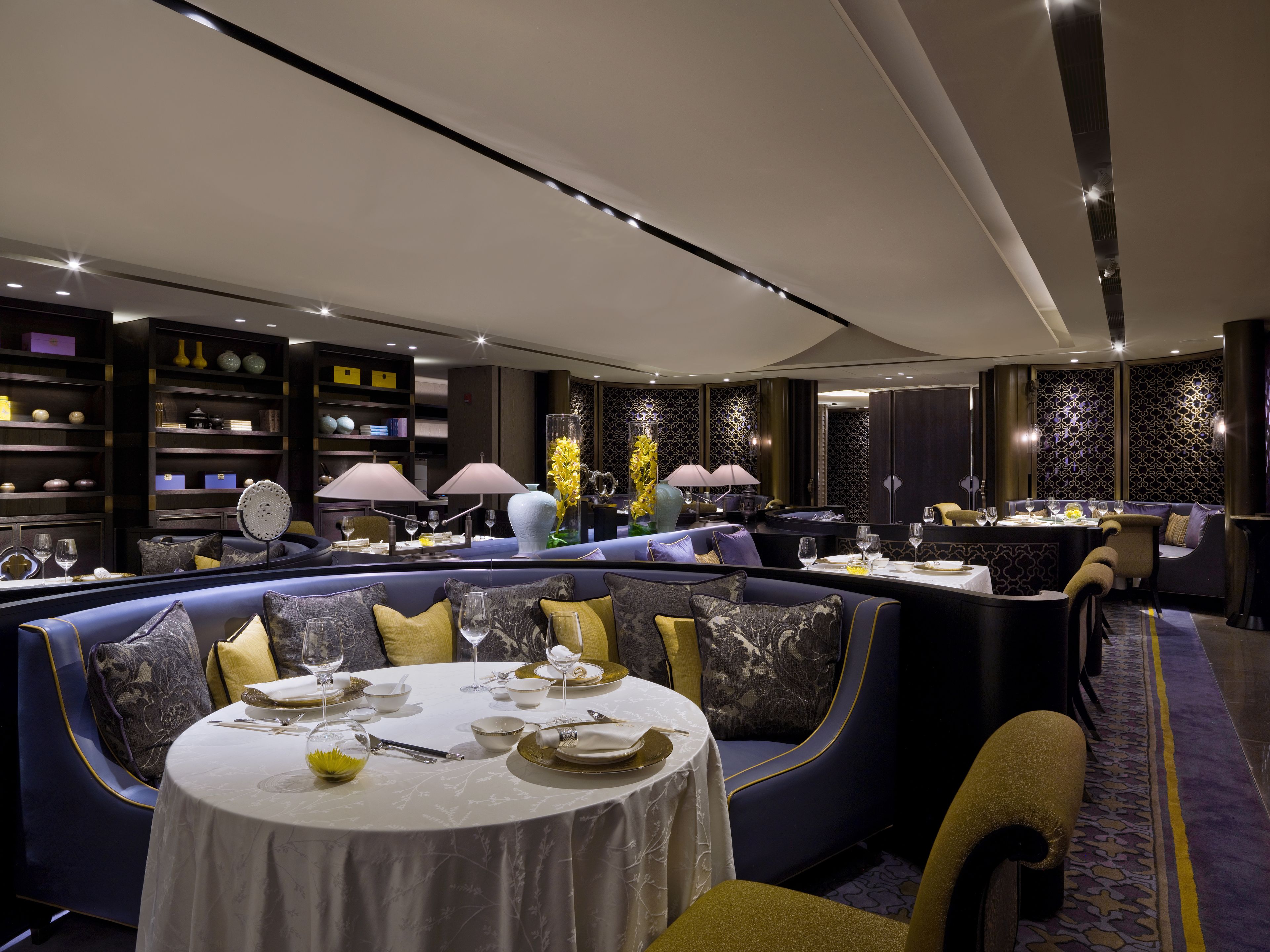 A modern dining area with round tables, blue upholstered seating, and decorative lamps.