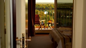 A hotel room with a bed, a small table with a laptop, a chair, and a balcony with a view of greenery. - Sol Victoria Hotel, Spa & Casino (Victoria)