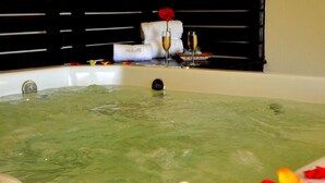A bathtub with rose petals, a flower, and champagne glasses. - Sol Victoria Hotel, Spa & Casino (Victoria)