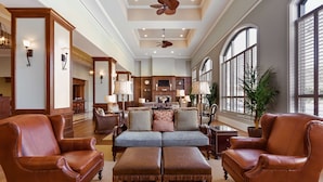 A spacious living room with leather armchairs, a sofa, and a ceiling fan. - Embassy Suites by Hilton Savannah Historic District (Savannah)