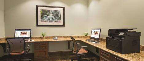 A professional office with two desks, chairs, a printer, and a framed picture on the wall.