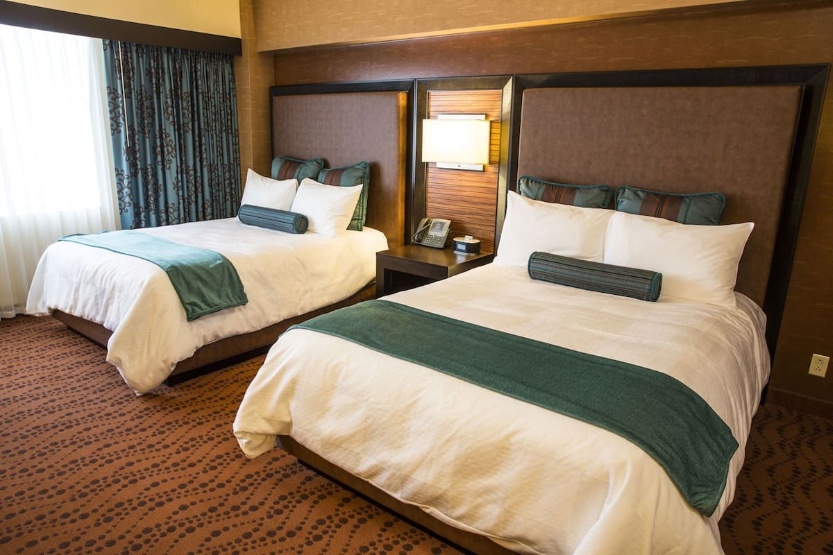 Two double beds with headboards, a bedside table with a lamp, and a patterned carpet.