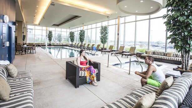 Amplia zona de piscina interior con asientos y vistas a la ciudad.