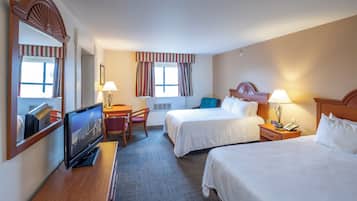 A hotel room with two beds, a desk with a TV, a chair, and a window with curtains.