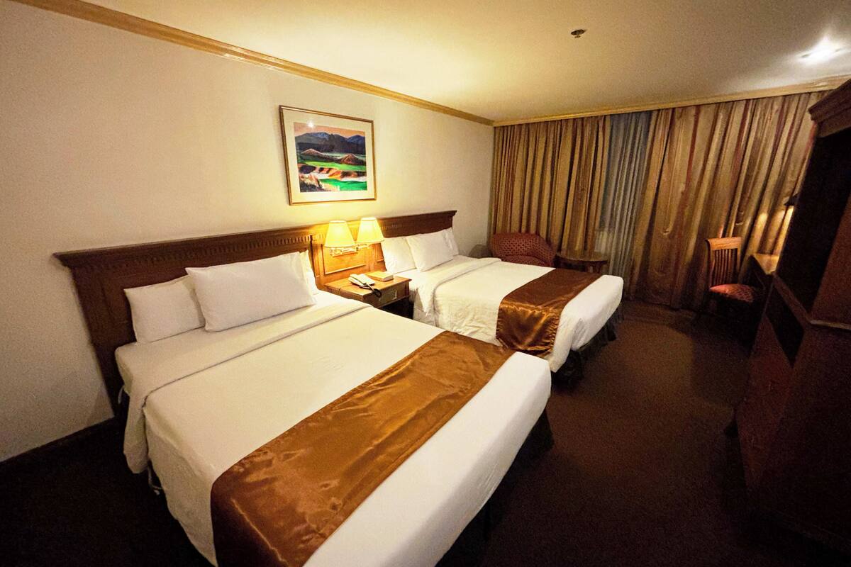 Una habitación de hotel con dos camas, un cuadro en la pared y una cortina.