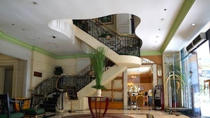 A lobby with a grand staircase, a reception desk, and a large potted plant. - Tiara Oriental Hotel Makati powered by Cocotel (Makati)