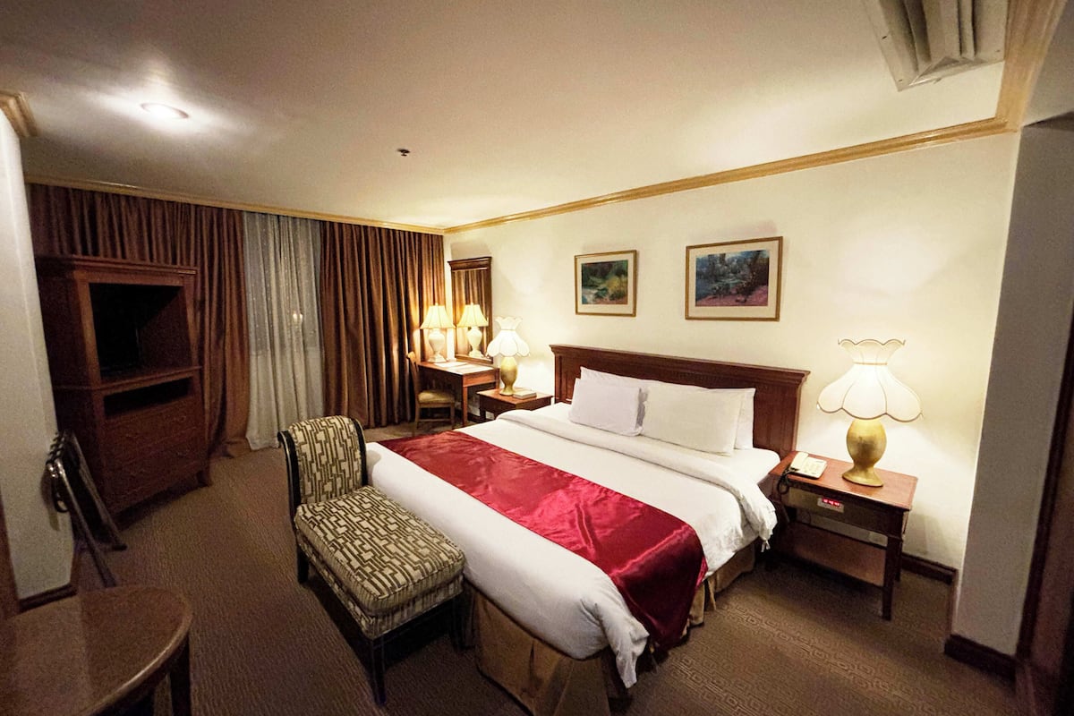 Una habitación de hotel con una cama grande, una silla, un escritorio y un televisor.