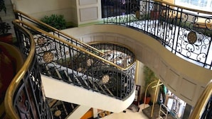 A multi-level interior with a curved staircase featuring ornate black railings and gold accents. - Tiara Oriental Hotel Makati powered by Cocotel (Makati)