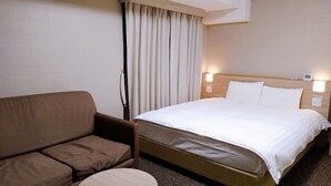 A hotel room with a bed, a brown sofa, and a small round table. - Dormy Inn Express Matsue (Matsue)