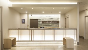 A reception area with a stone wall background, a reception desk, and two wooden benches. - Dormy Inn Express Matsue (Matsue)