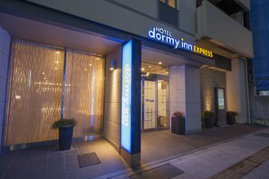 L'ingresso moderno di un hotel con un'insegna ben visibile per 'Hotel Dormy Inn Express'.