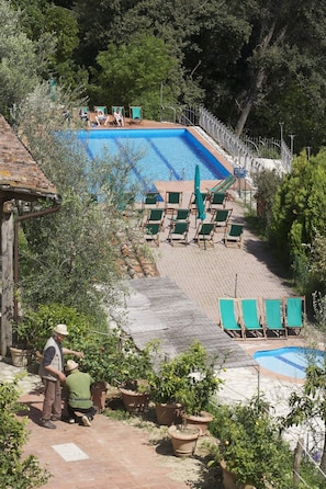 Ein Poolbereich mit Liegestühlen und einem kleinen Garten.