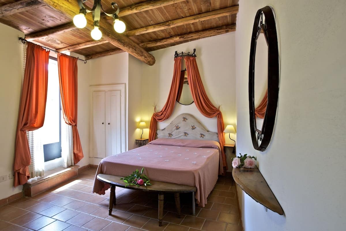 Un dormitorio con cama con dosel, techo de madera y una pequeña mesa con un arreglo floral.