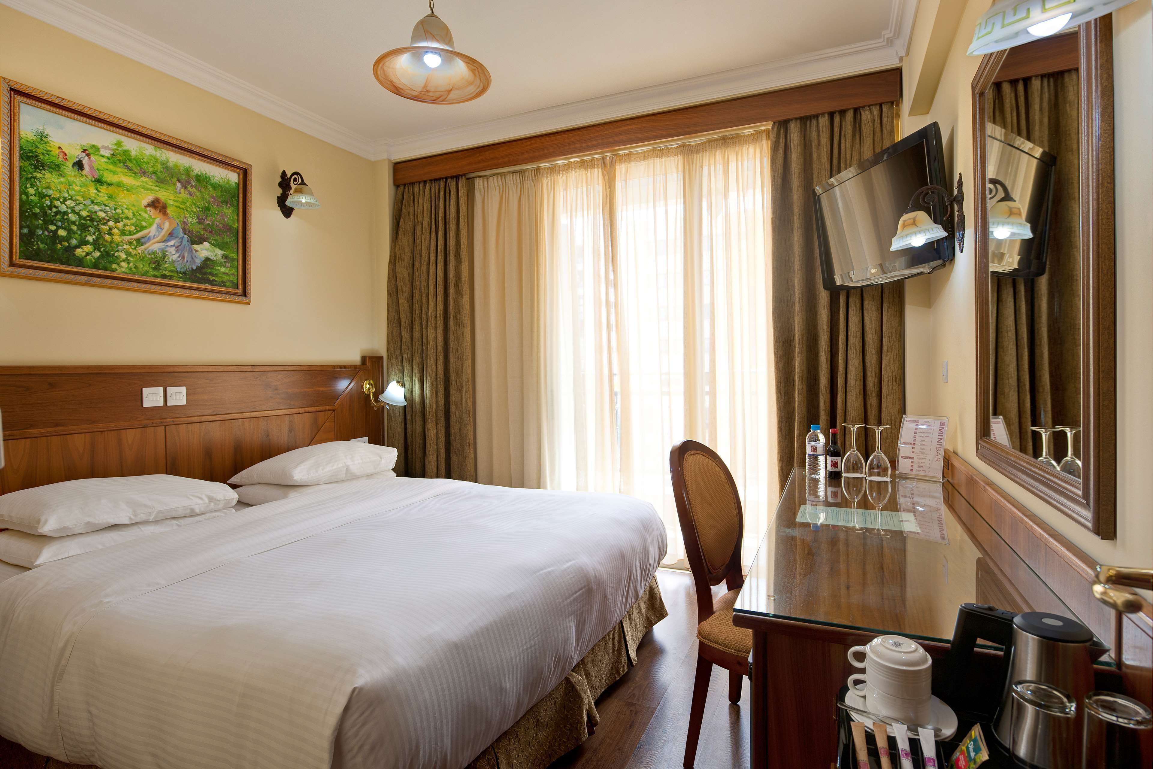 Habitación de hotel con una cama grande, un escritorio con silla, cafetera y televisión.