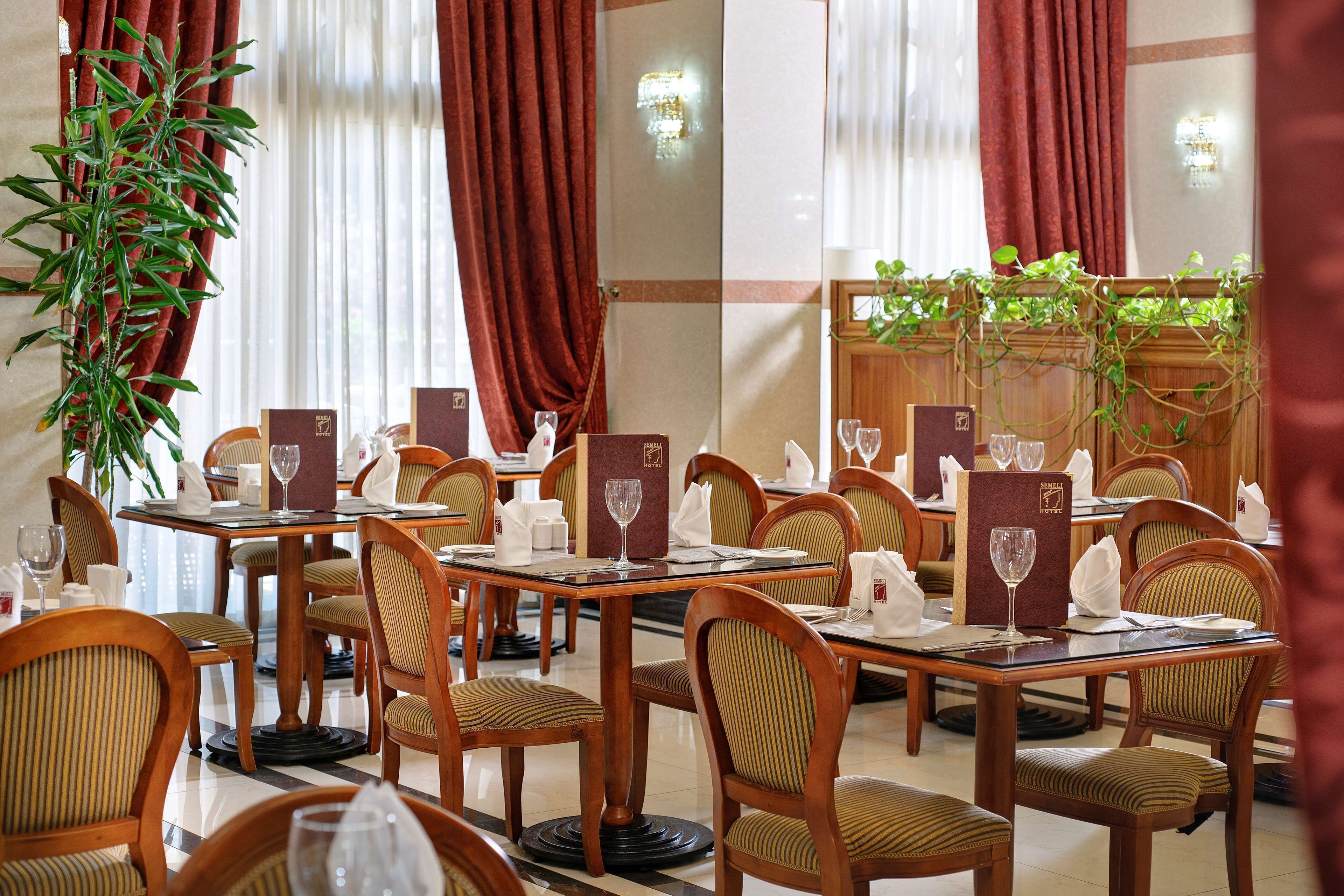 Un restaurante con mesas y sillas de madera, menús y copas de vino.