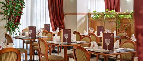 Un restaurante con mesas y sillas de madera, menús y copas de vino.