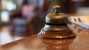 A close-up of a brass bell on a polished wooden surface, likely a reception area.