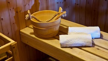 Un banco de madera con un cuenco de madera y una toalla con el bordado "SEMPELI".