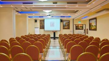 A conference room with rows of chairs, a projector screen, and a podium.