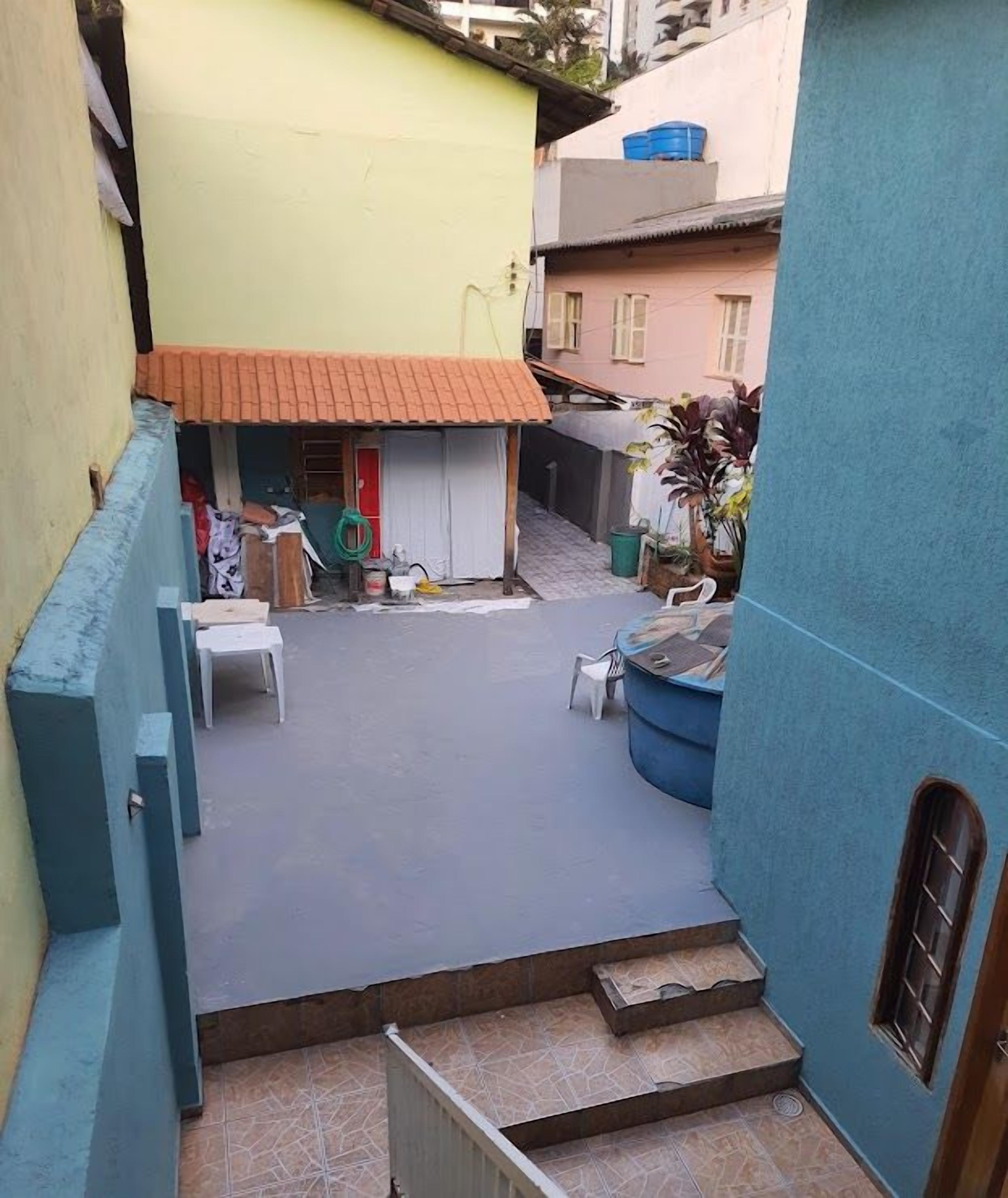 Um pátio com um pequeno edifício, mobiliário externo e uma parede azul.
