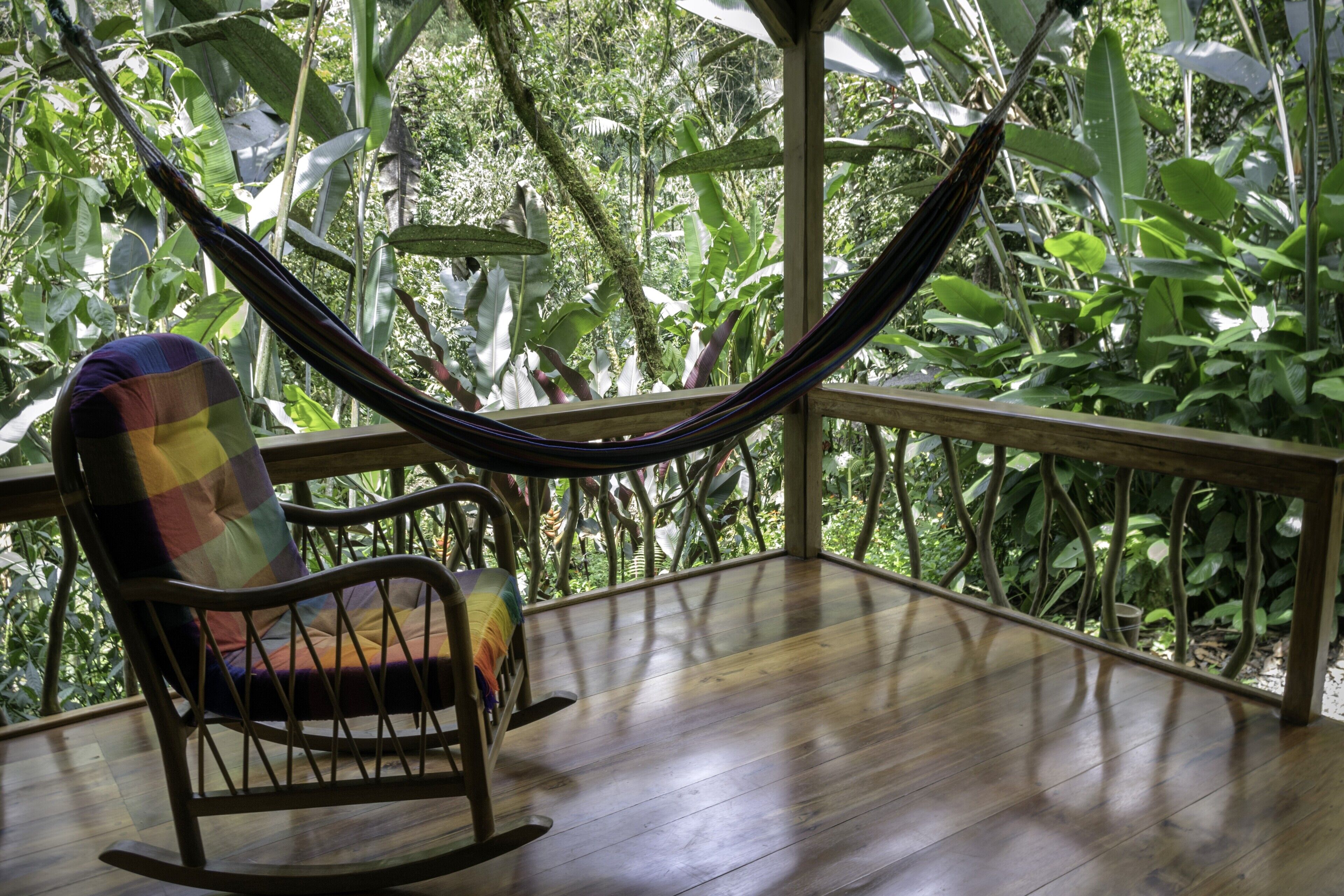 A wooden deck with a rocking chair and a hammock.