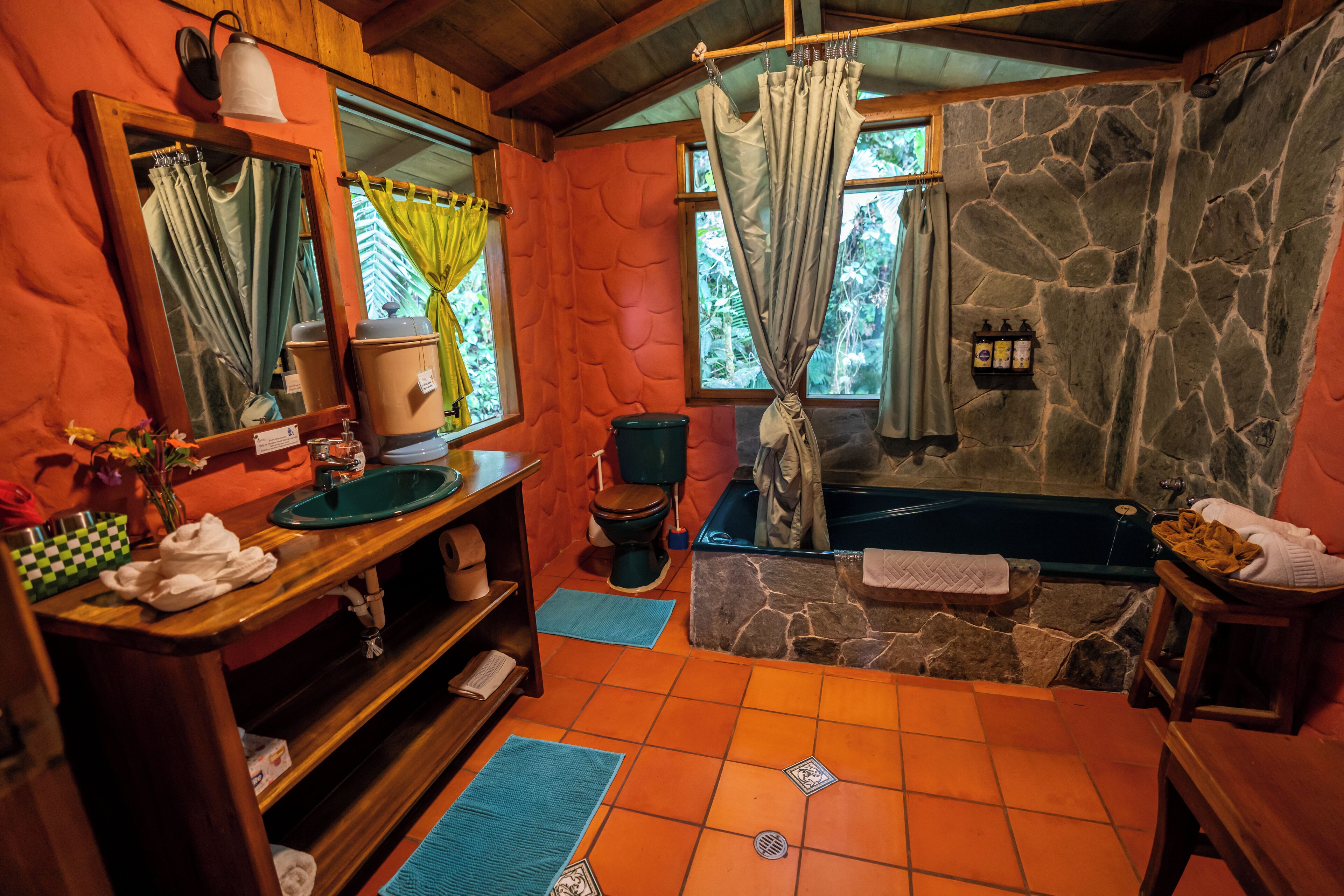 Une salle de bain avec un mur en pierre, une baignoire, des toilettes, un lavabo et un miroir.