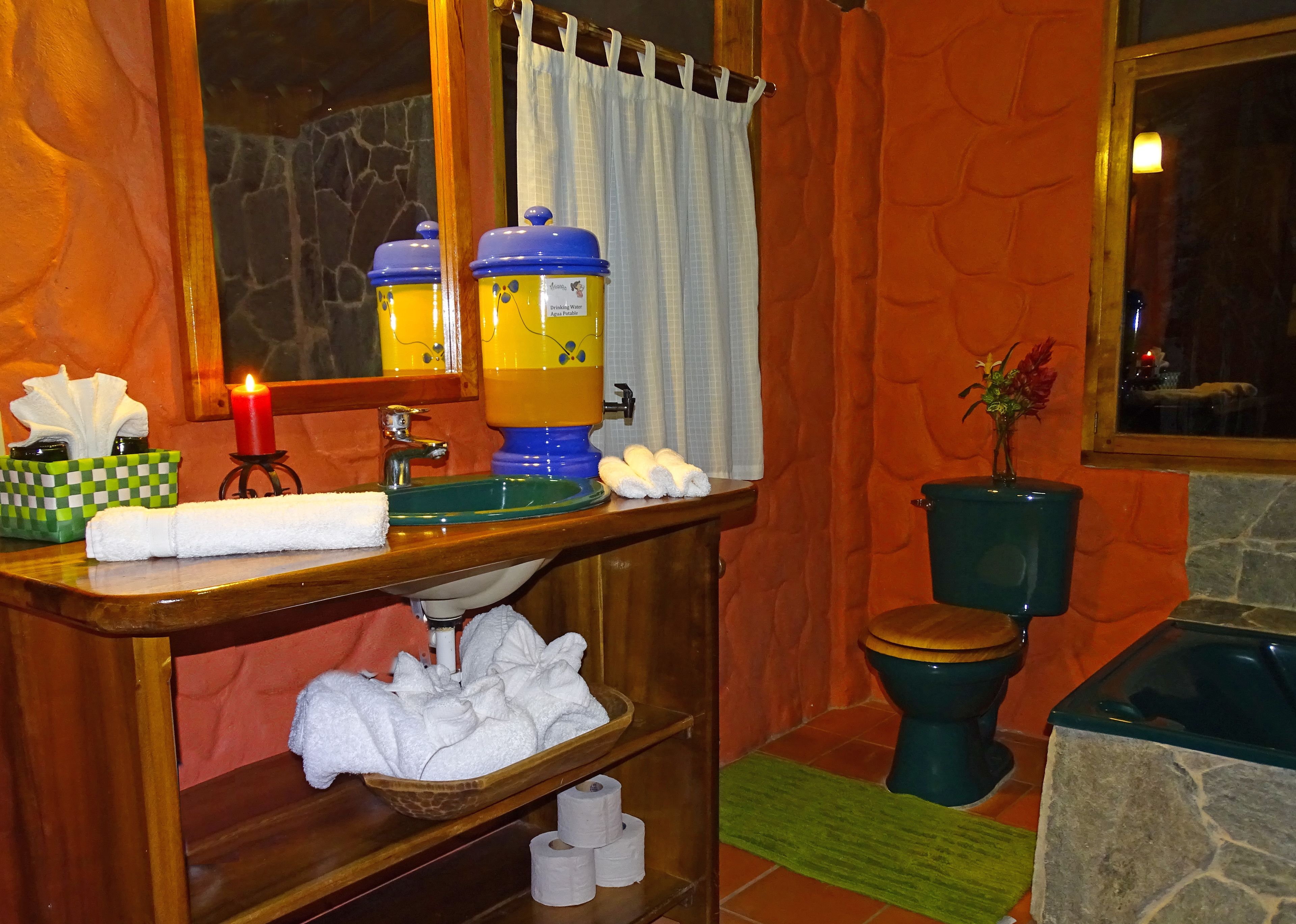 A bathroom with a wooden vanity, a green sink, a toilet, and a green bathtub.
