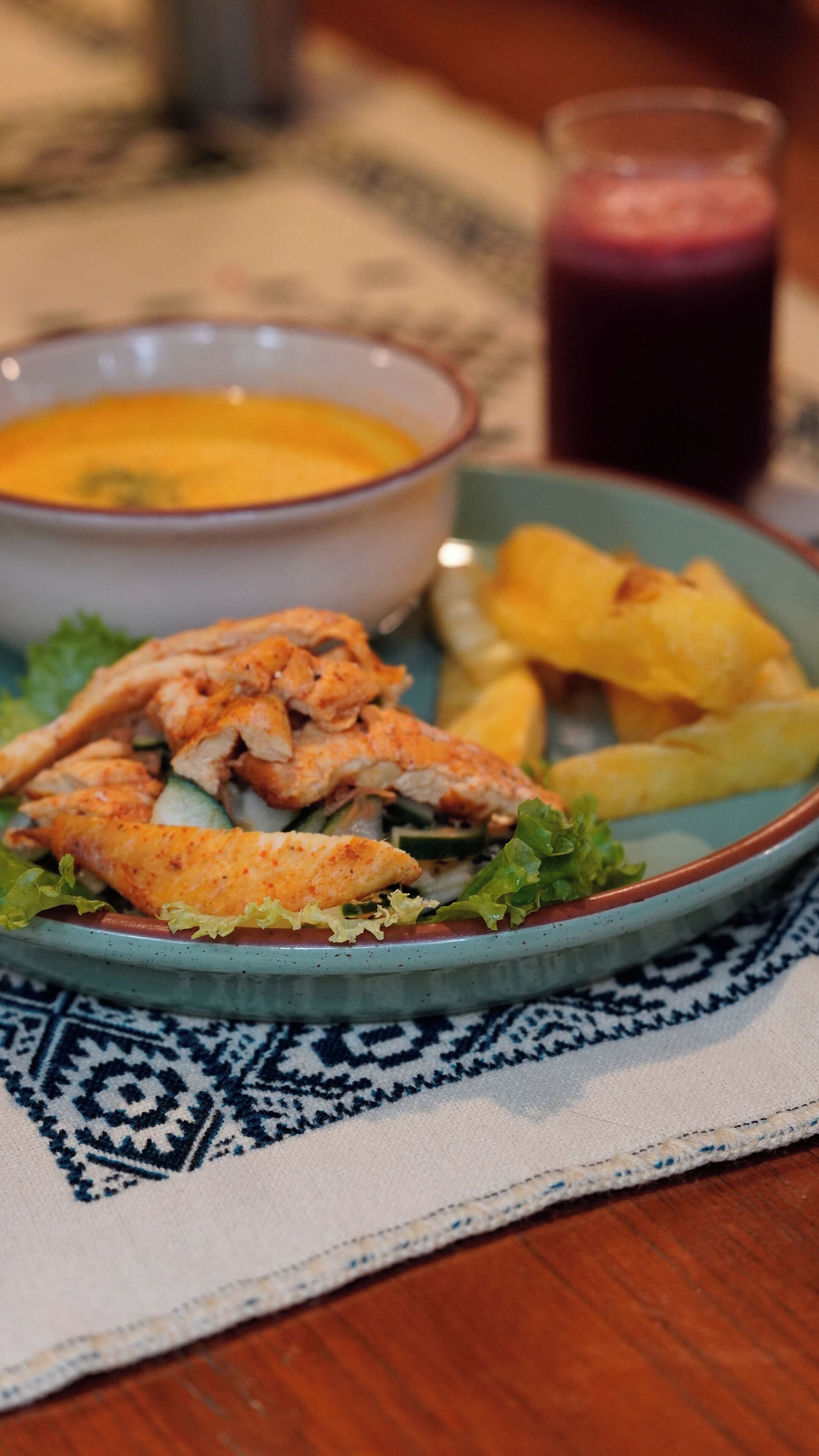 A plate of food with a bowl of soup and a glass of beverage.