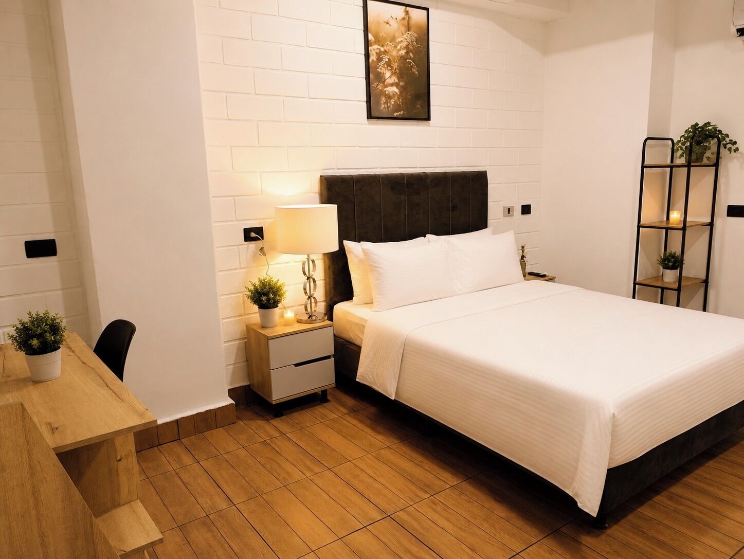 Quarto de hotel com cama, mesa de cabeceira, abajur e quadro na parede.