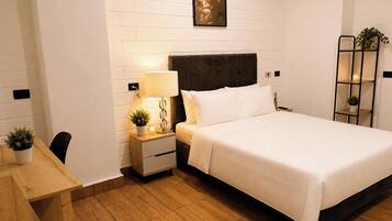 Una habitación de hotel con cama, mesita de noche, lámpara y un cuadro en la pared.