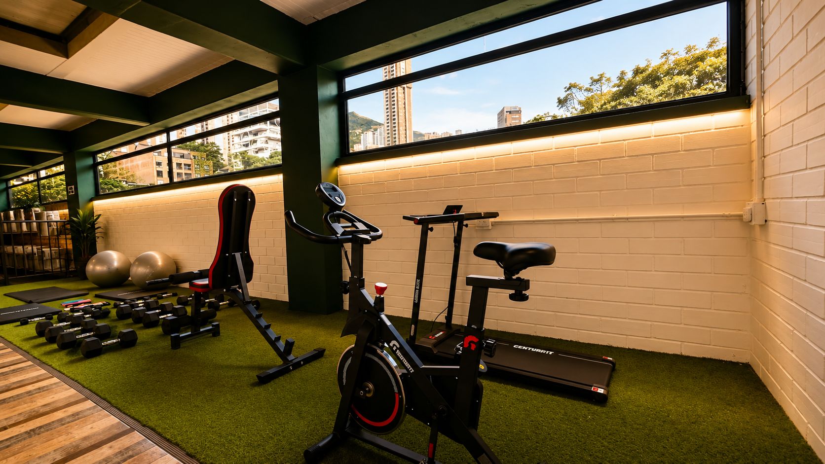 Ein Fitnessraum mit Trainingsgeräten, Laufband und Blick auf Gebäude durch große Fenster.