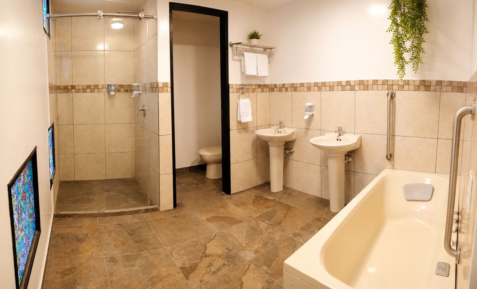 Een badkamer met douche, toilet, twee wasbakken en een bad.