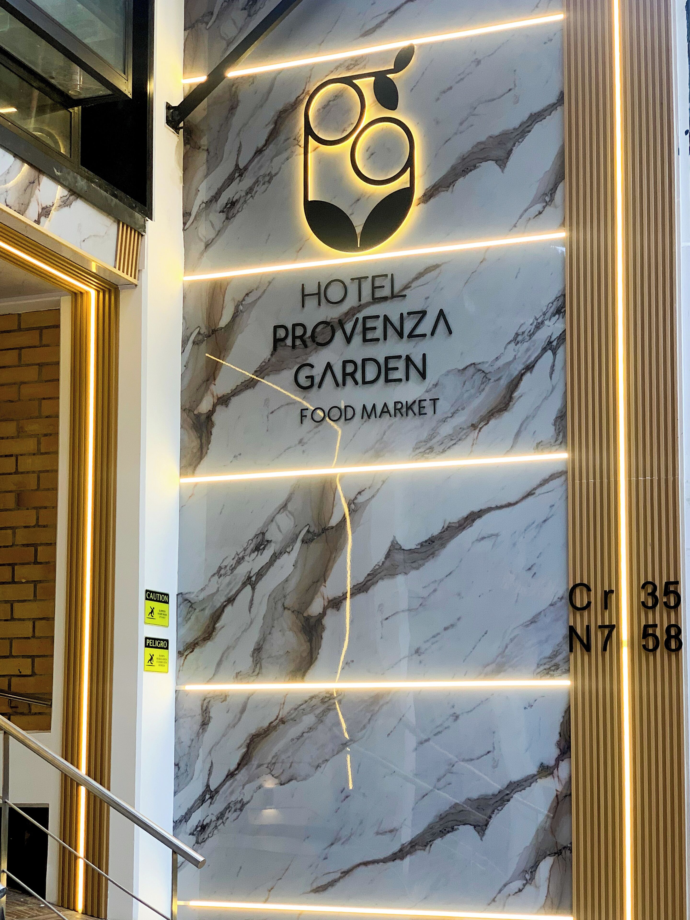 Una pared de mármol con el texto “HOTEL PROVENZA GARDEN FOOD MARKET” y un logotipo en la parte superior.