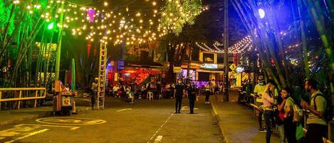 A street at night with string lights and people.