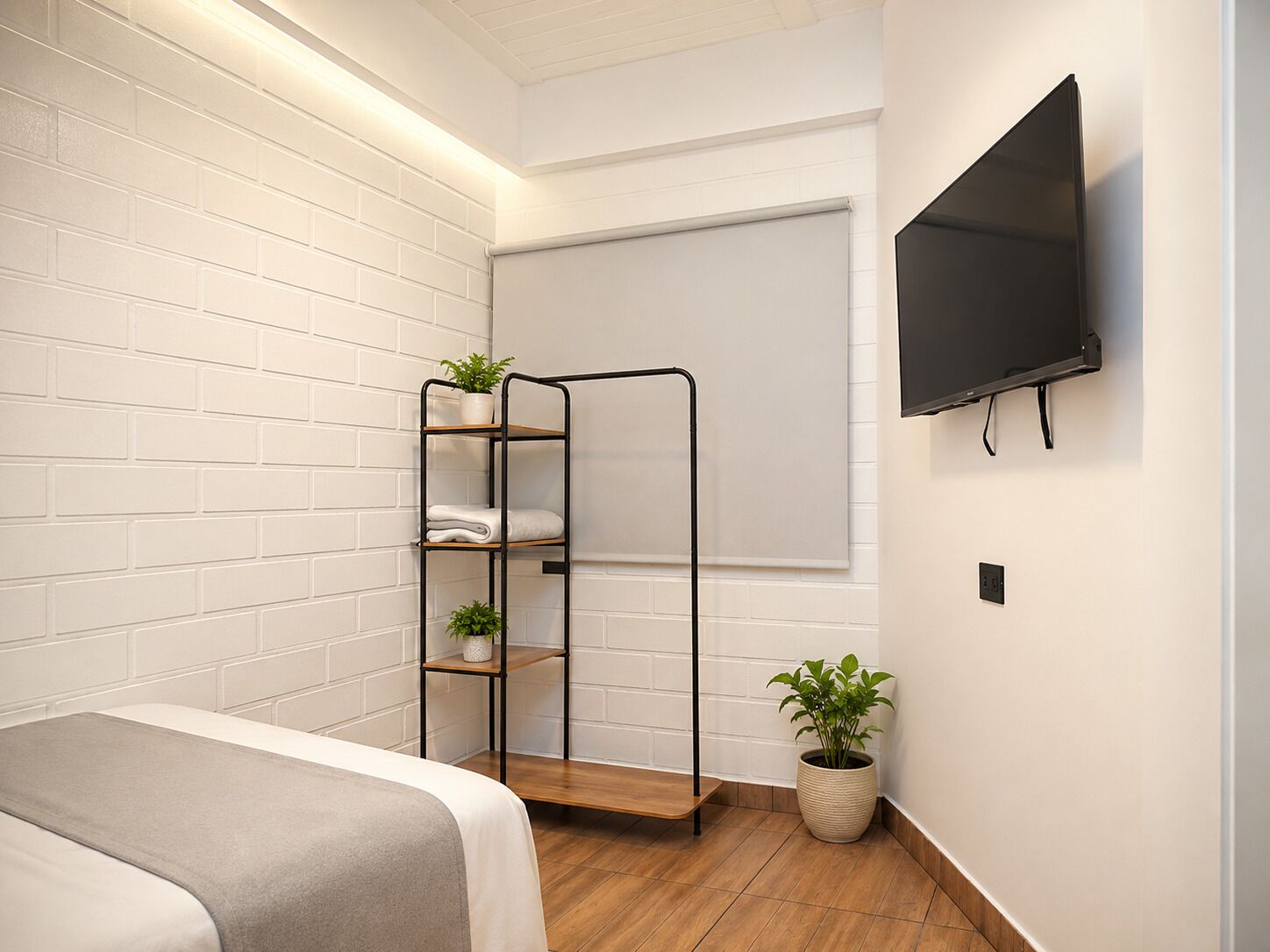 Un dormitorio con una cama, un televisor de pared, una estantería con plantas y una ventana con persiana.