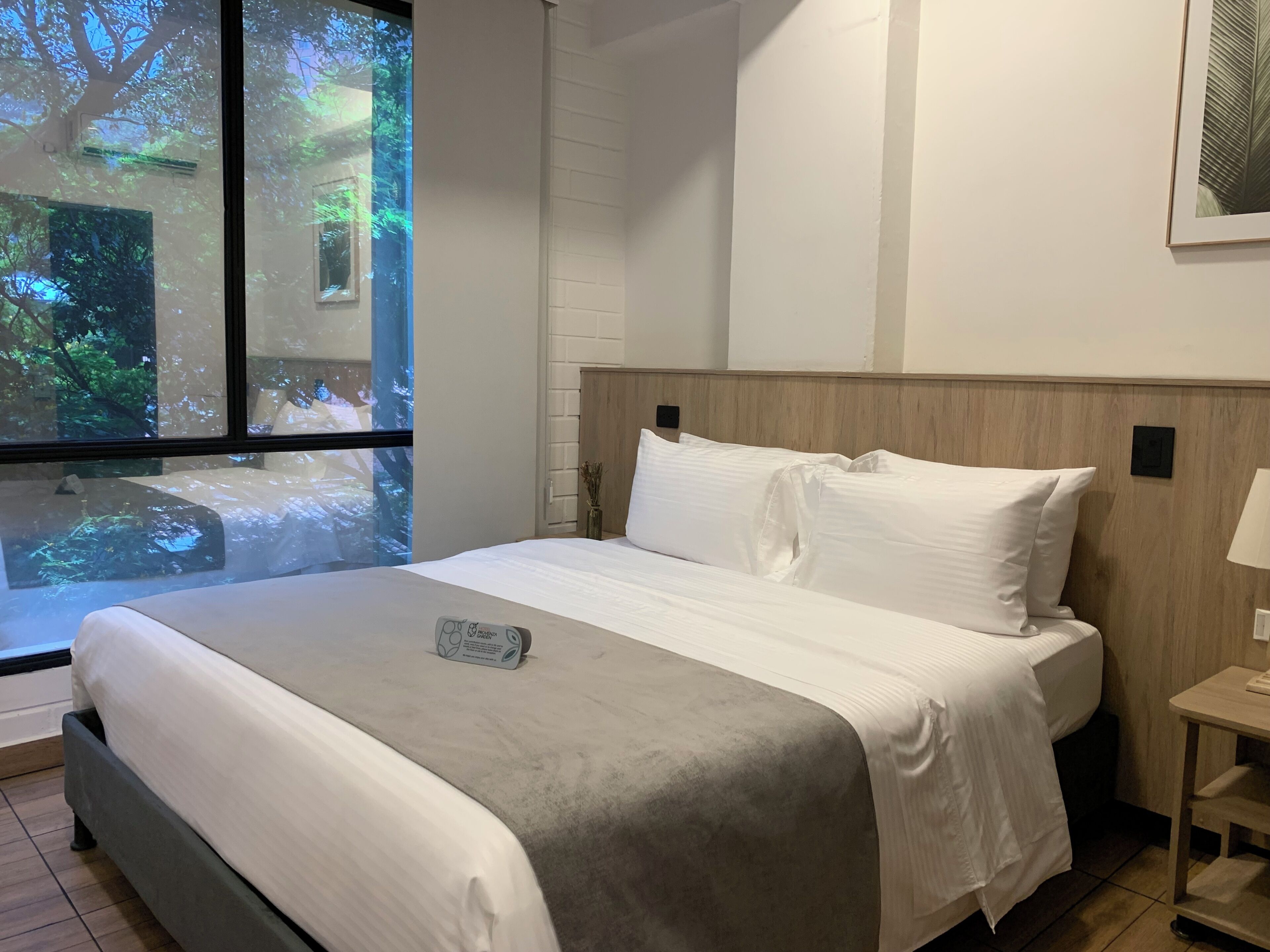 Una cama bien hecha con sábanas blancas, un detalle en gris y un pequeño adorno sobre la cama.