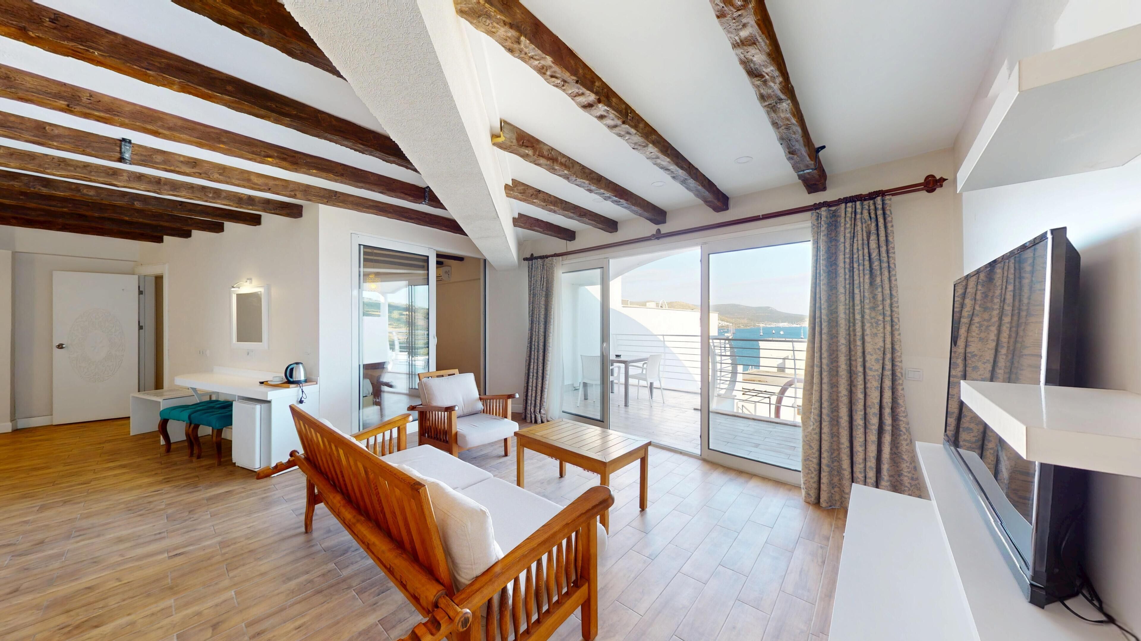 Un vaste espace de vie agrémenté de poutres en bois, un balcon avec vue et un téléviseur à écran plat.