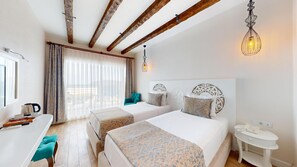 A hotel room with two beds, a desk with a kettle, and a view of the beach. - Casa Mare Bodrum (Bodrum)