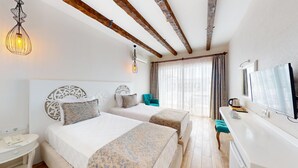 Ein Hotelzimmer mit zwei Betten, einem Fernseher, einer Kaffeemaschine und einem Fenster mit Vorhängen.