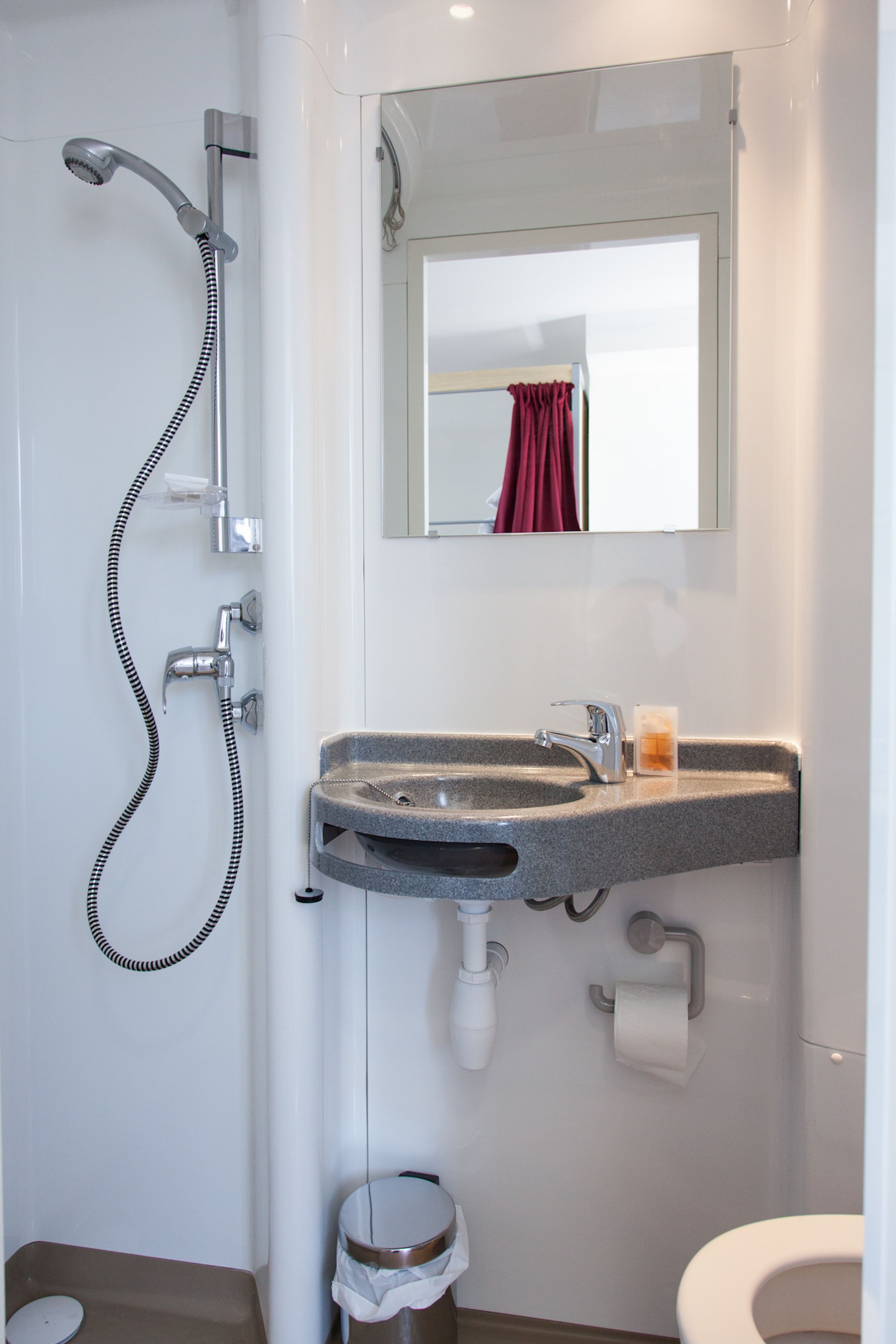 A bathroom with a shower, sink, toilet, and a mirror.