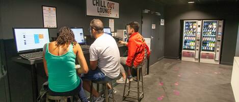Eine Lounge zum Entspannen mit Barhocker, Computern und einem Automaten.