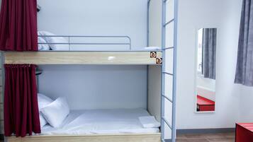 Habitación con literas, una litera inferior, un espejo y una silla roja.
