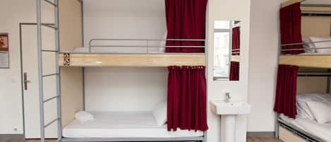 A bunk bed room with a ladder, a sink, and a mirror.