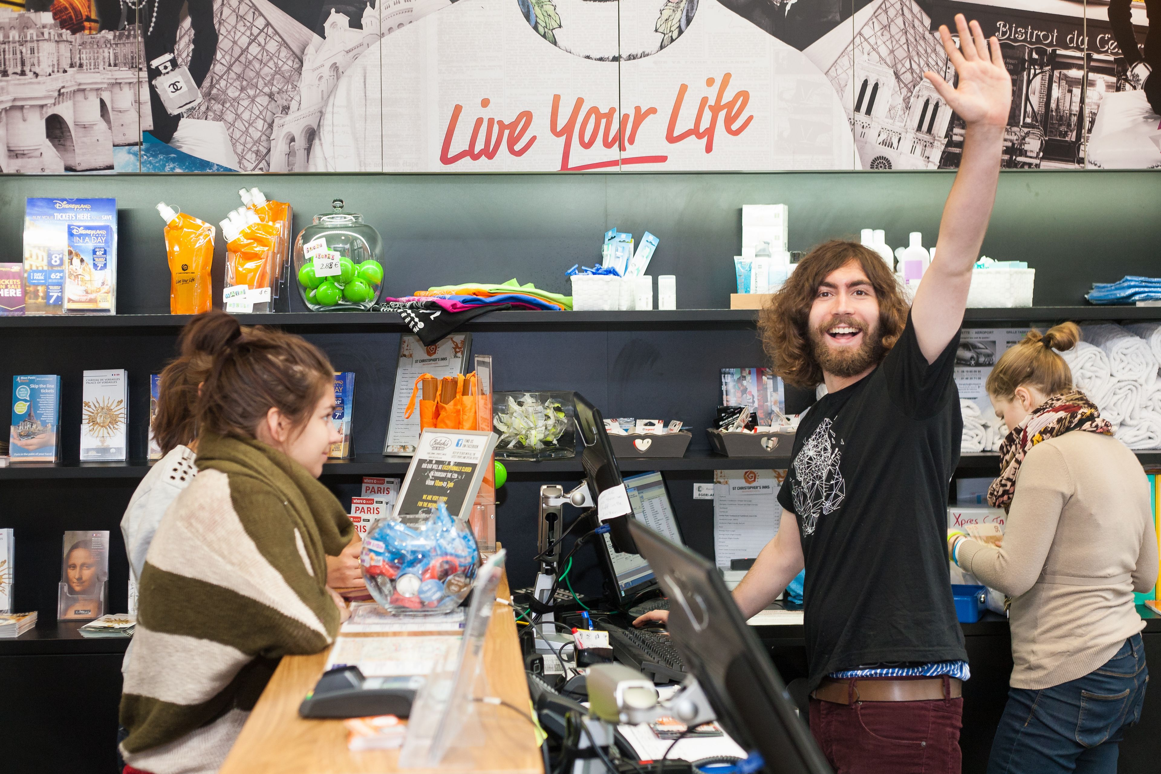 A bookstore with a 'Live Your Life' sign, shelves with books, and a checkout counter.