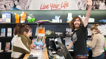 Een boekwinkel met een bord dat 'Live Your Life' zegt, boekenplanken vol boeken en een kassa.
