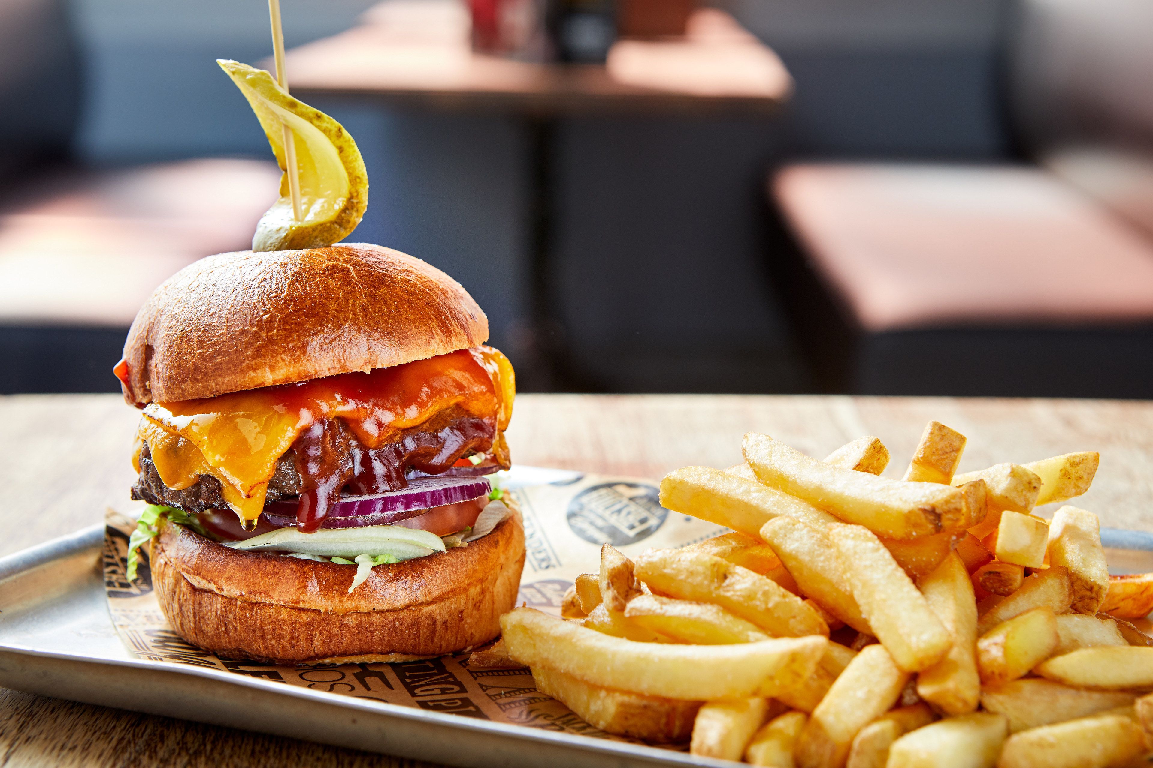 A burger with fries on a tray.