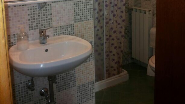 Une salle de bain avec un lavabo, un miroir, une douche et des murs carrelés.