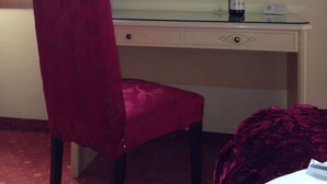 Una habitación con un escritorio, una silla, una botella de vino y una copa sobre el escritorio.