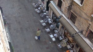 Un patio con mobiliario exterior, un perro con correa y gente caminando.